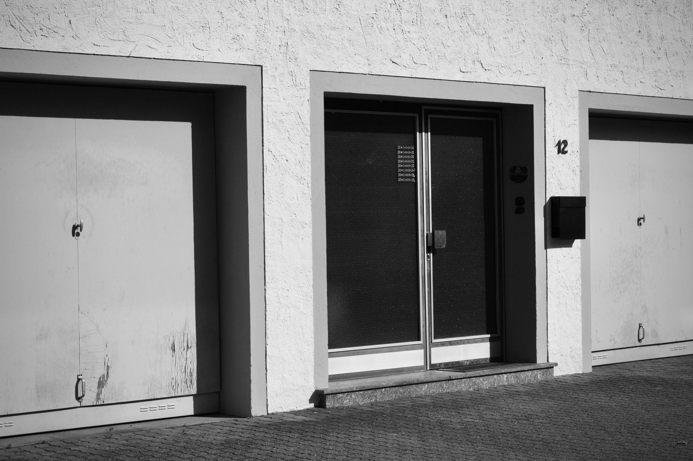 Garage doors beside a private entrance door on a light stucco building