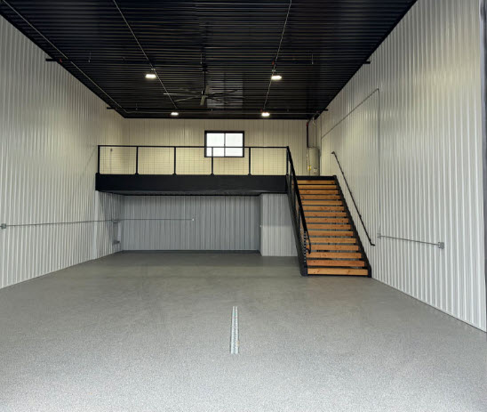 Interior of an empty Prime Flex Parks unit with mezzanine, stairs and sealed concrete floor