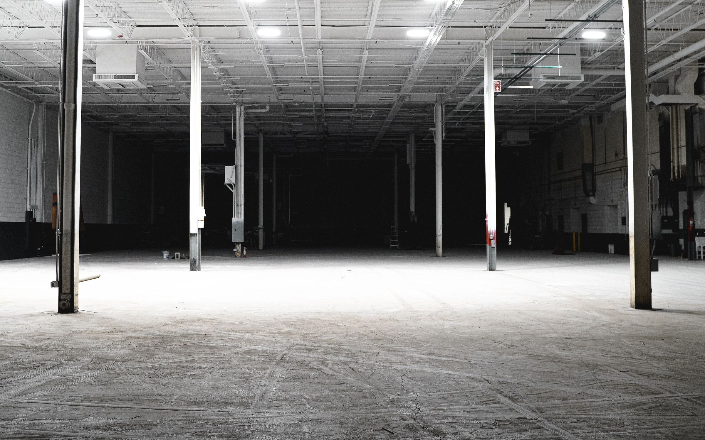 Empty industrial warehouse interior with steel support columns and overhead lighting